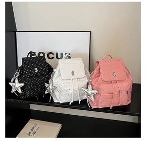 Detailed view of three mini nylon backpacks with star prints and silver star pendants