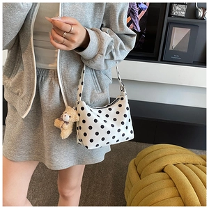 Detail einer weißen gepunkteten Segeltuchtasche mit einem süßen braunen Bären-Anhänger