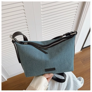 Dettaglio della borsa hobo in denim blu con tracolla in pelle nera e cerniera argento