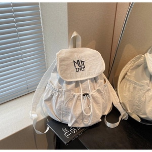 Close-up of white nylon backpack featuring black MUTING embroidery and drawstring design