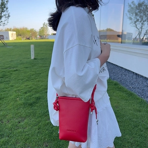 Détail du petit sac rouge texturé avec bandoulière à nœuds et finition soignée