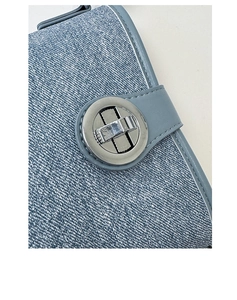Macro view of light blue denim bucket bag featuring a round silver metal twist lock