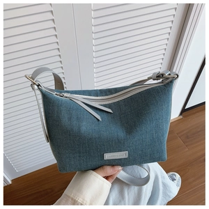 Dettaglio della borsa a tracolla in denim lavato con cinturino in pelle grigia e zip