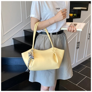 Detail of light yellow pebble leather tote bag with a checkered silk scarf charm