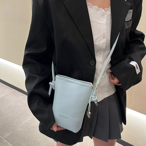 Détail du mini sac bleu clair avec bandoulière nouée et pendentif coeur argenté