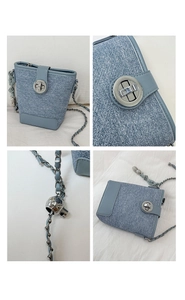 Detail of light blue denim bucket bag featuring silver chain strap and metal swivel lock