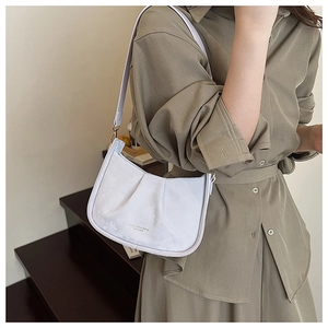 Détail du sac à bandoulière plissé violet clair en cuir sur un mannequin en robe verte