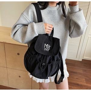 Detailansicht eines schwarzen Nylon-Rucksacks mit MUTING-Stickerei auf der Klappe