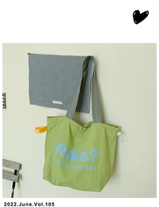 Detail of green canvas tote with grey handles and blue slogan print in street style