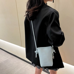 Gros plan d'un sac seau bleu clair avec texture litchi et bandoulière fine en cuir