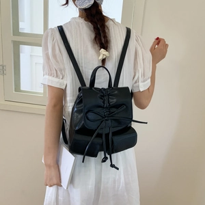 Detail view of black PU leather backpack with elegant bow and drawstring closure on model