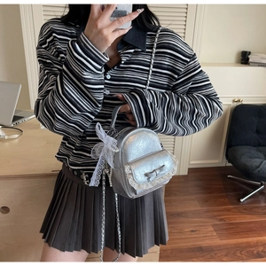 Détail du mini sac à dos argenté avec nœud en dentelle, chaîne en perles et cuir froissé