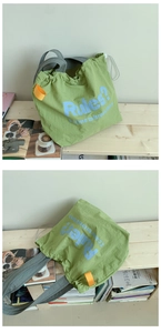 Makroaufnahme der grünen Kordelzug-Tasche mit Slogan und Nylon-Falten-Textur