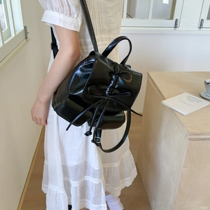 Rear view of a stylish black PU leather backpack with bow detail worn by a model