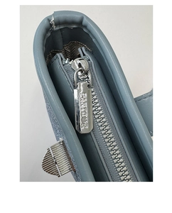 Macro shot of blue bucket bag showing textured leather, silver zipper, and metallic details