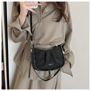 Détail du sac seau noir en demi-lune avec texture plissée et finitions métalliques dorées