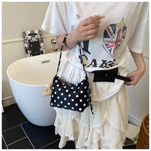 Detail of trendy black polka dot shoulder bag and mini waist bag worn with lace skirt
