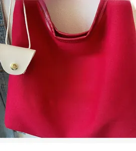 Détail du sac cabas en toile rouge avec broderie jaune et mini breloque en cuir