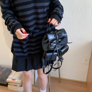 Close-up of black PU leather backpack with drawstring bow detail and glossy finish
