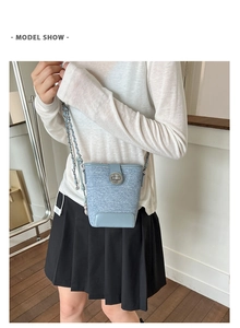 Close-up of stylish light blue bucket bag featuring a silver twist-lock and chain strap