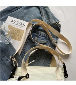 Overhead view of off-white canvas tote bag with adjustable strap on blue denim jacket