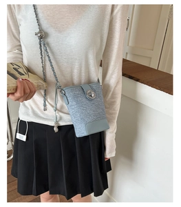 Detail of light blue bucket bag with metal chain strap and spherical adjustment bead