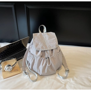 Detail view of light gray nylon backpack with 'NUT ING' embroidery and drawstring closure
