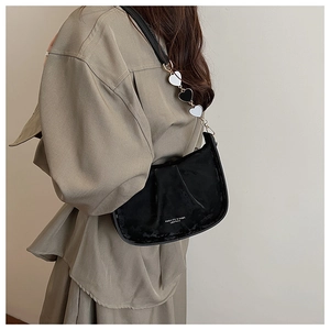 Détail du sac à bandoulière noir plissé avec pendentif coeur et texte de mode