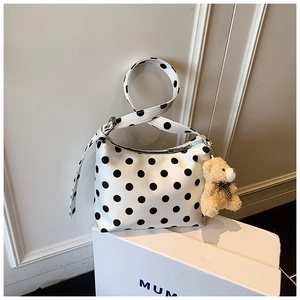 Detailansicht der Polka-Dot-Tasche mit Plüschbären-Anhänger auf weißem Podest
