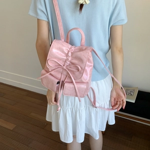 Pink mini PU leather backpack with bow detail shown on a model for scale and style