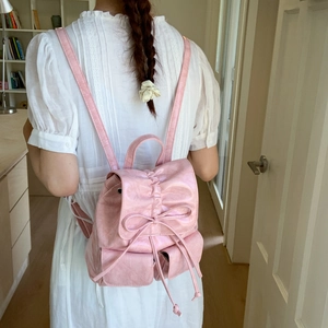 Detail showing pink ruffled backpack with drawstring bow and front pockets on model