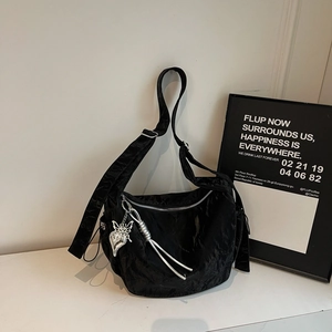 Detail of black pleated crossbody bag with silver butterfly charm and metal zipper