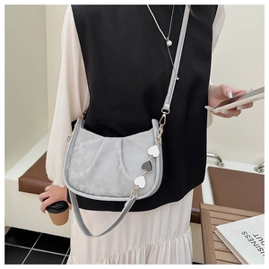 Photo lifestyle d'un sac demi-lune gris avec breloques cœur et finition mate élégante