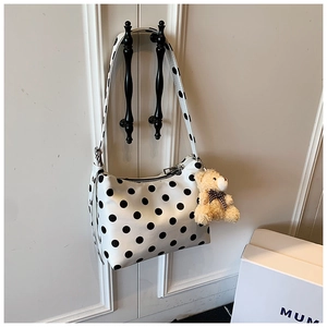 Detailaufnahme der weißen Polka-Dot-Schultertasche mit niedlichem Plüschbären-Anhänger
