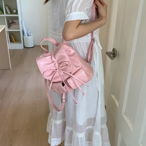 Pink faux leather backpack featuring a decorative bow, drawstring closure, and side pockets