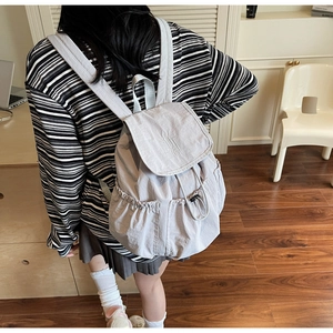 Detail view of a light gray nylon backpack with drawstring and MUTING embroidery