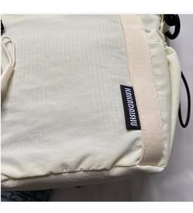 Detail of off-white nylon sports bag featuring brand label and tactical rope zipper pulls