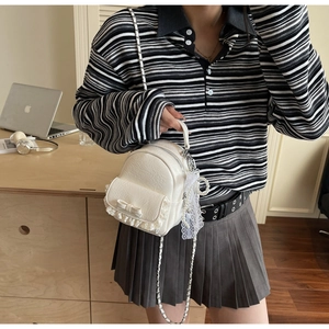 Mini sac à dos blanc avec bordure en dentelle, nœud et charm de perles en détail