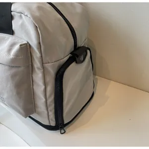 Detailed macro view of the smooth black zipper and nylon webbing on a grey travel bag
