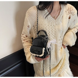 Mini sac à dos en cuir verni noir avec dentelle et nœud porté par un mannequin