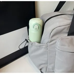 Detail of grey nylon travel bag showing a side drawstring pocket with a water bottle