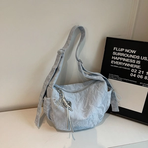 Close-up of light blue pleated nylon crescent bag with silver butterfly charm detail