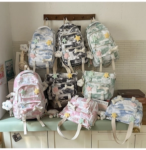 Detail view of tie-dye backpacks and tote bags with cute plush charms on a wooden rack