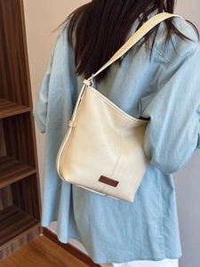 Chic cream leather bucket shoulder bag for women styled in a minimalist city commute look
