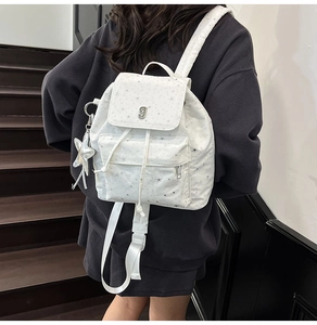 Back view of white canvas backpack with grey star patterns and silver star charm