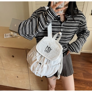 Detail shot of white nylon drawstring backpack with black MUTING logo on the front panel