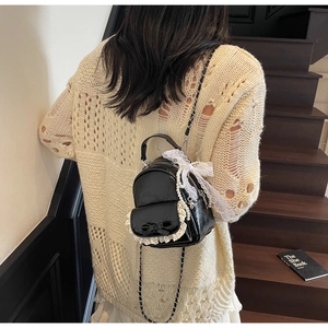 Mini sac à dos en cuir verni noir avec dentelle, nœud perlé et bandoulières en chaîne