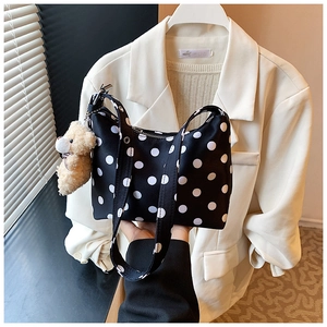 Detail einer schwarzen Polka-Dot-Segeltuchtasche mit einem süßen braunen Plüschbären