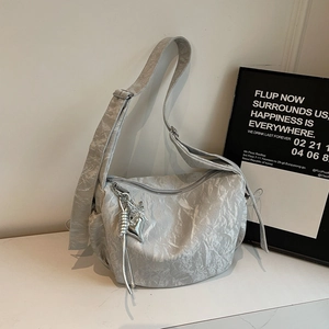 Detailed close-up of silver crinkled shoulder bag with heart charm and wide strap
