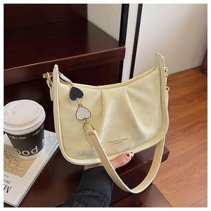 Détail du sac à bandoulière plissé jaune crème avec pendentif cœur sur bois